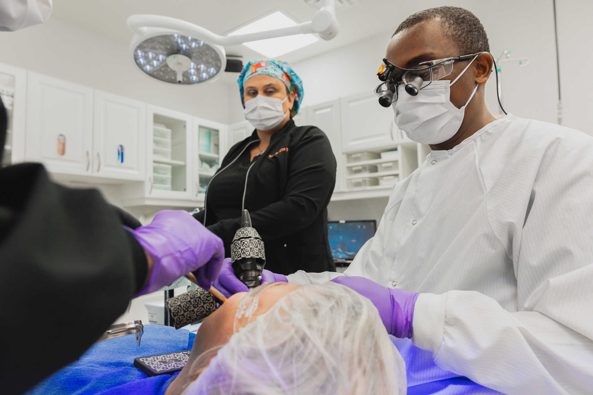 Our oral surgeon near Harford County performs a routine biopsy on a patient. The patient is lying on their back in a private dental room, with various dental tools being used by our oral surgeon.