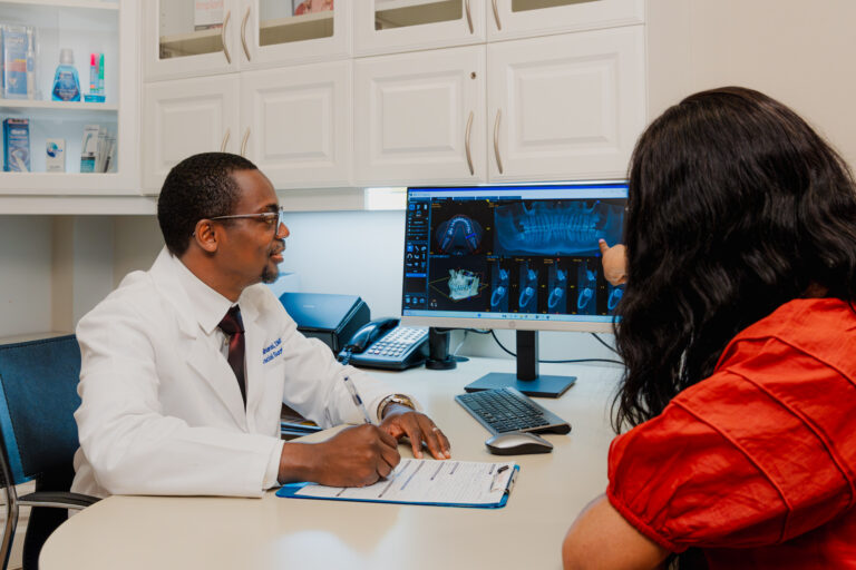 Our oral surgeon at the Krupp Center sits with a patient, examining an X-ray. X-rays are a common pre-op step to take before receiving dental procedures in Towson.